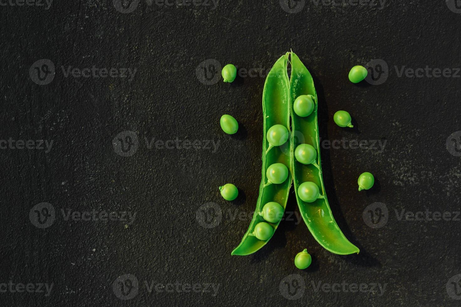 Vegetable backdrop vith copy space for your projects. Close up of fresh ripe green peas on black background photo