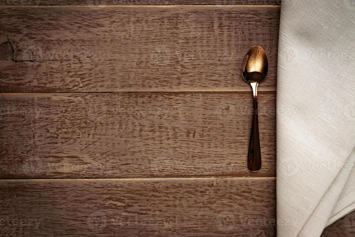 Top view of cloth napkin of beige color and served tea spoon on wooden table. photo