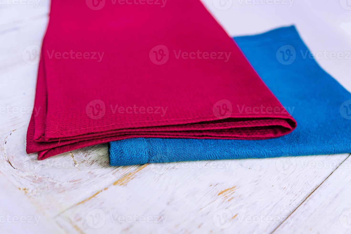 close up of cloth napkins of blue and burgundy colors on rustic white wooden table. Shallow depth of field. photo