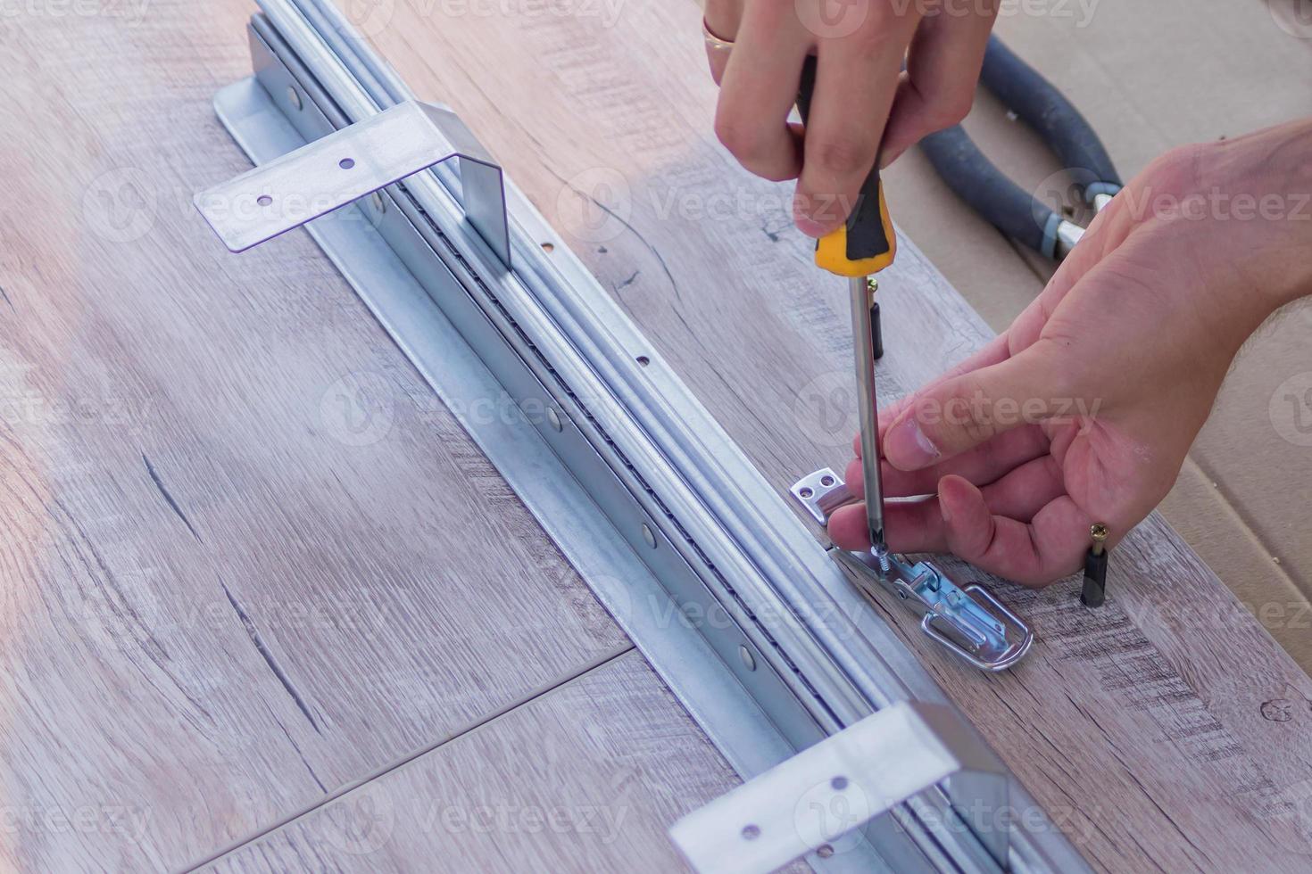 furniture assembling - Carpentry screws for a knock down wooden table. photo