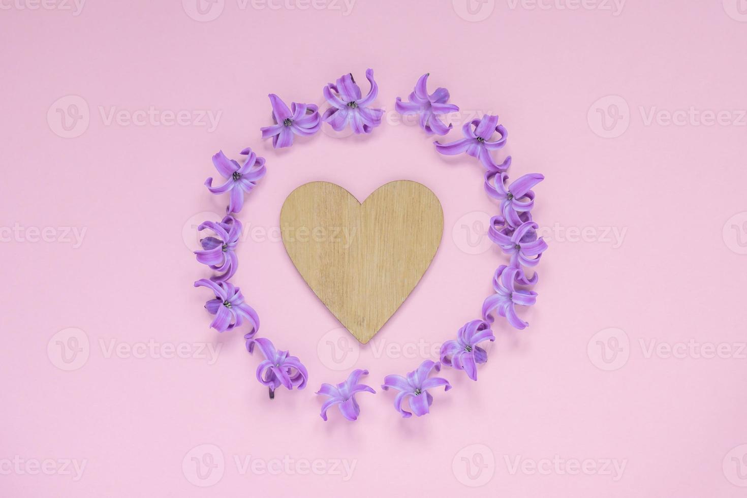 Round frame of pastel purple hyecinth flowers and wooden heart on gradient pink background. Floral wreath. Layout for holidays greeting of Mothers day, birthday, wedding or other happy event photo