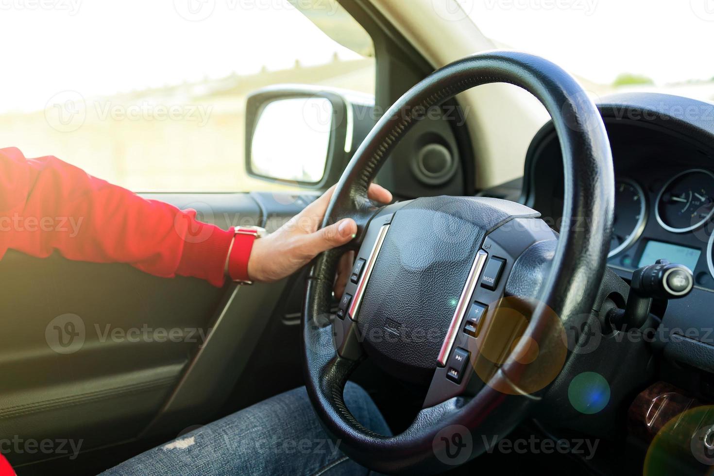 Man in red sweatshirt driving a car in a sunny day. traveling concept. photo