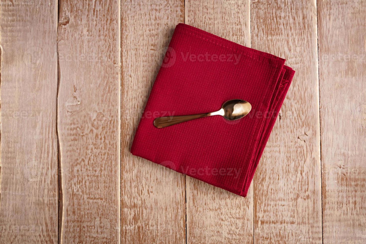 Top view of cloth napkin of beige color and served tea spoon on wooden table. photo