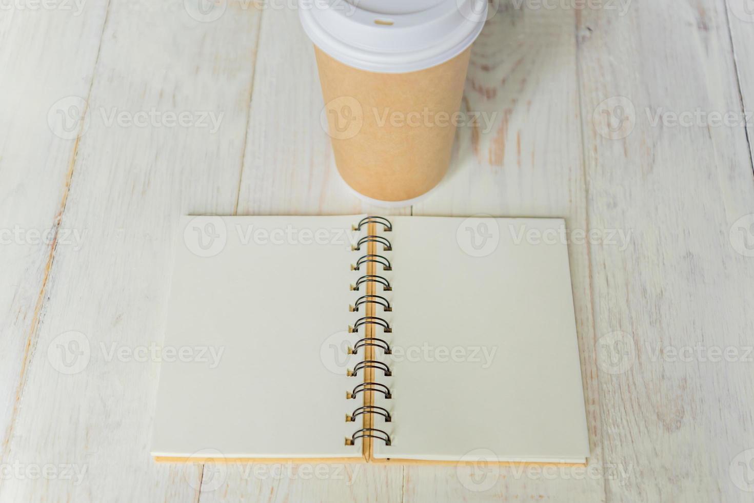 craft paper coffee cup and open notebook diary with copy space on wooden table photo
