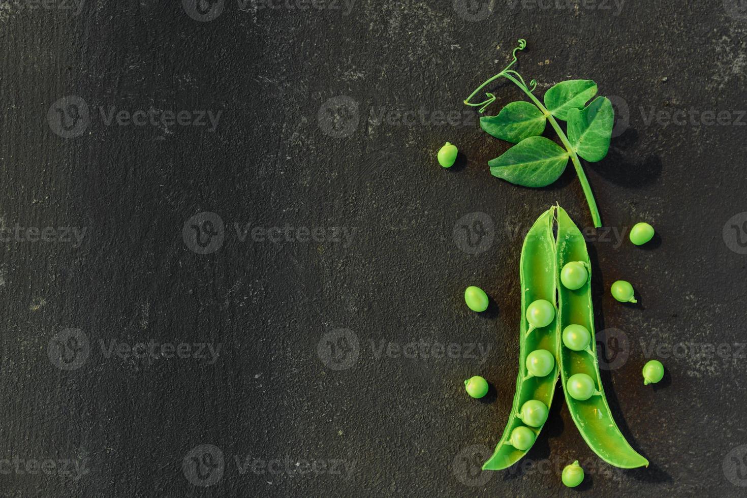Vegetable backdrop vith copy space for your projects. Close up of fresh ripe green peas on black background photo