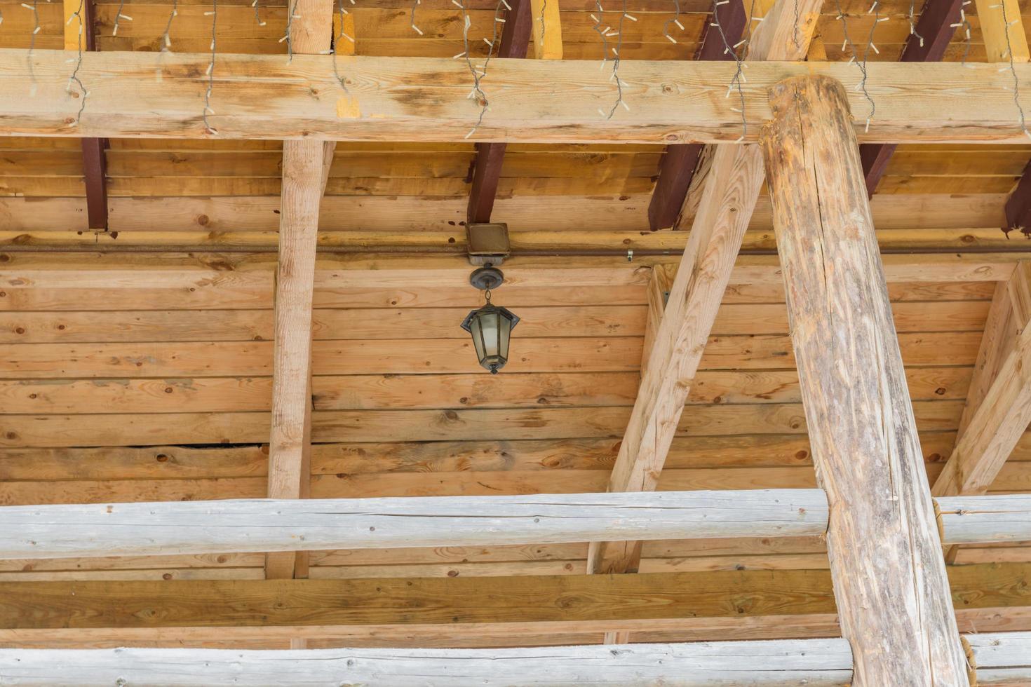 techo de madera de la casa de troncos decorado con guirnaldas y farol vintage foto