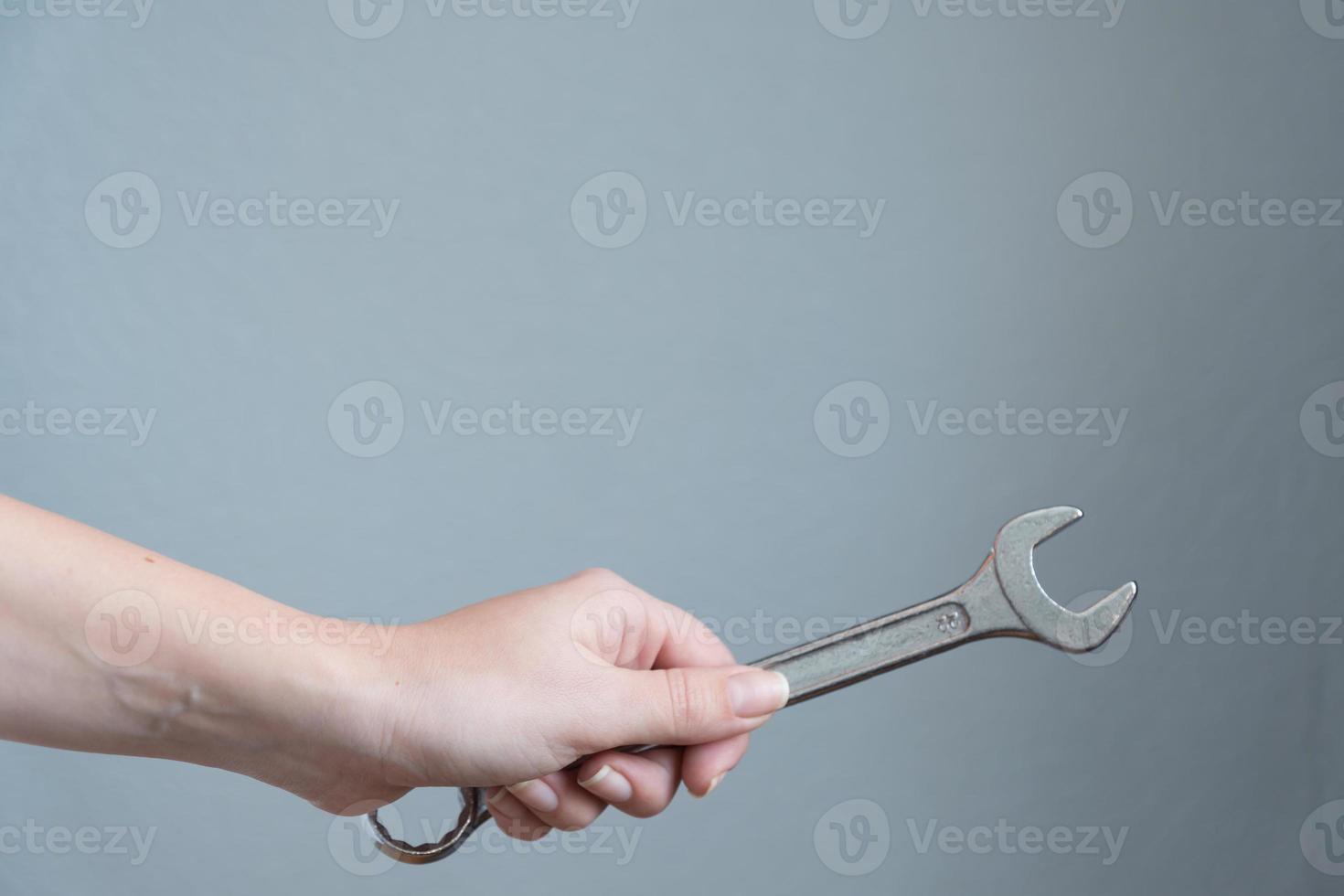 mujer sosteniendo una llave en la mano sobre fondo gris. foto