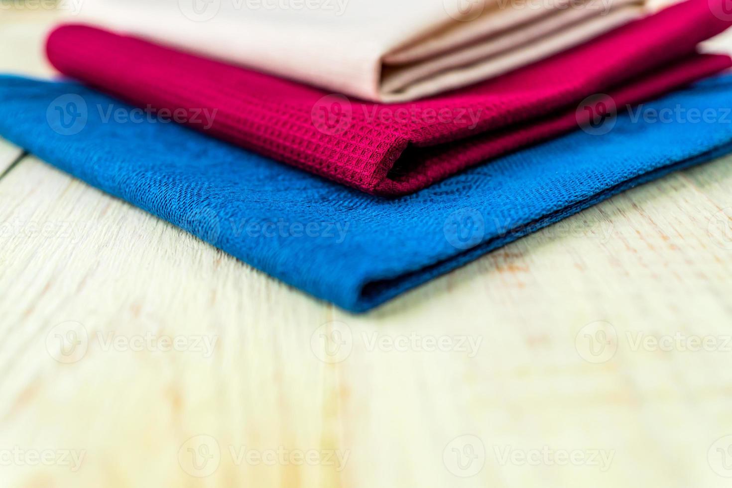 close up of cloth napkins of beige, blue and burgundy colors on rustic white wooden table. Shallow depth of field. photo