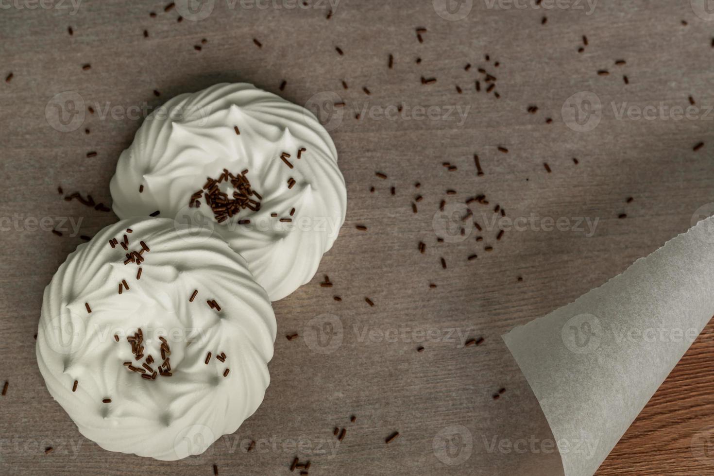 top view of homemade white air meringues and confectionery decorations on  on parchment paper. photo
