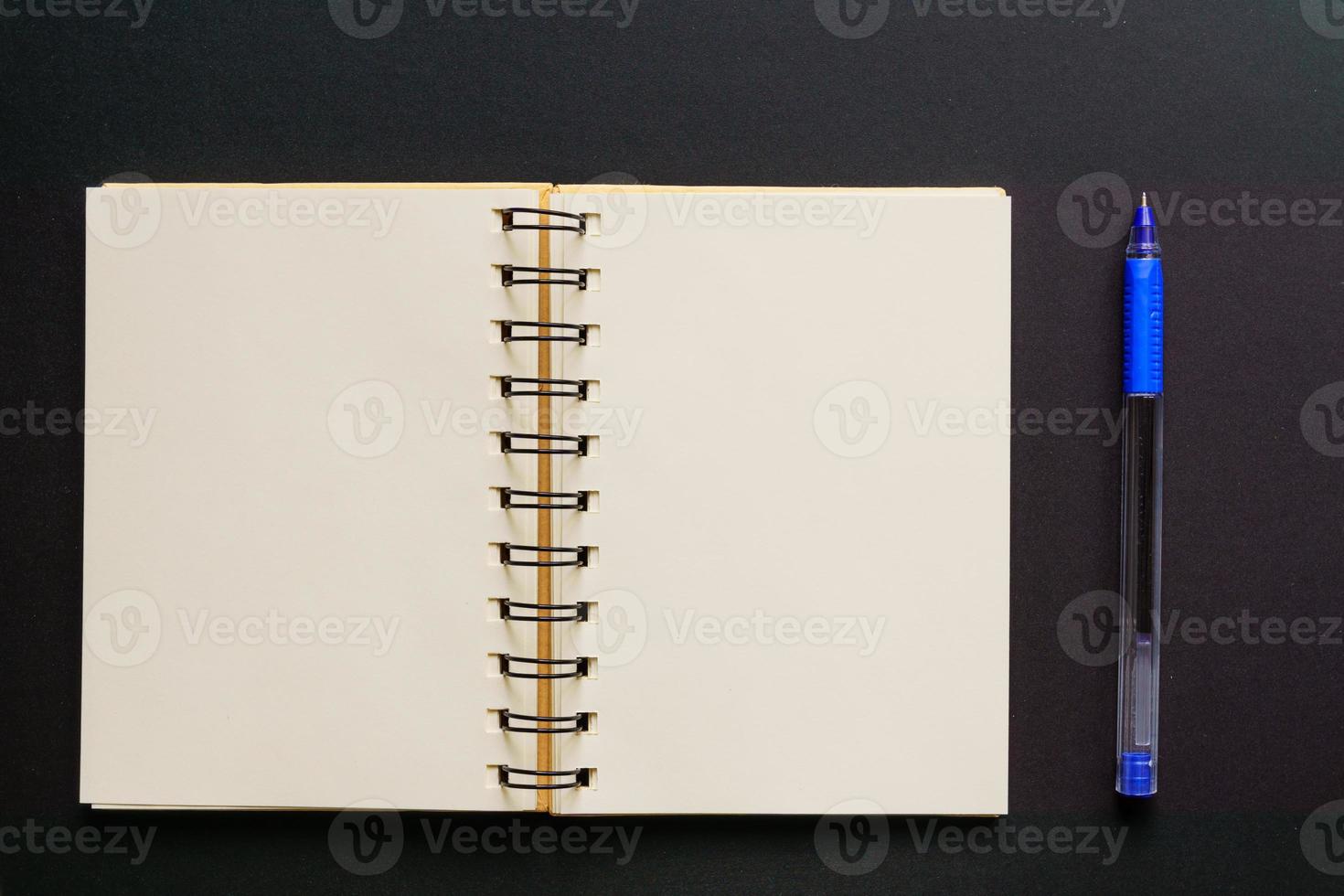 Design concept - Top view of empty kraft notebook and blue ballpoint pen on black background. mock up. photo