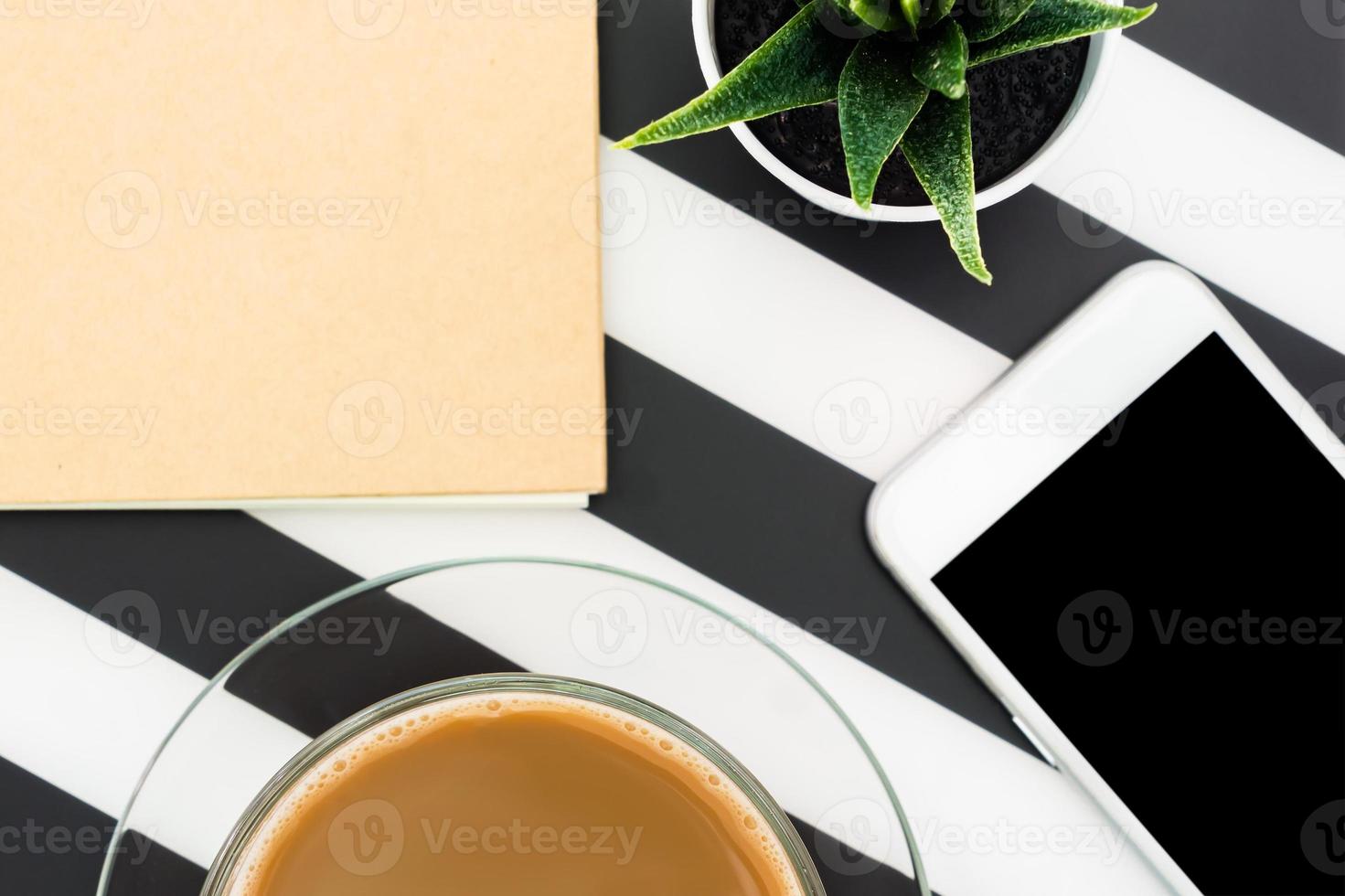 Stylish minimalistic workspace with notebook, pen, cup of coffee, smartphone and succulent on striped black and white background. Flat lay style Top view. photo