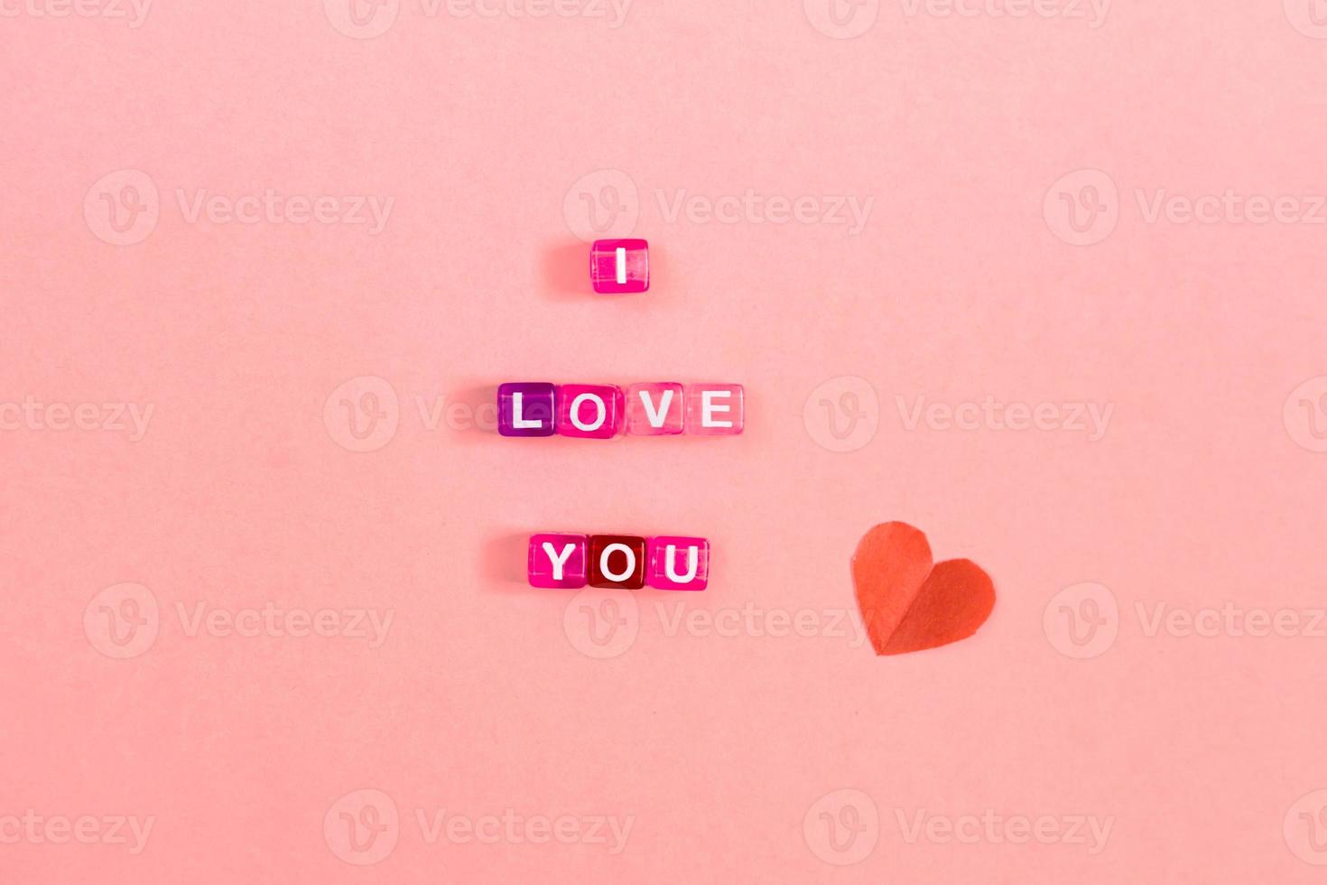 Love you  inscription made of colorful cube beads with letters. Festive pink background concept with copy space photo