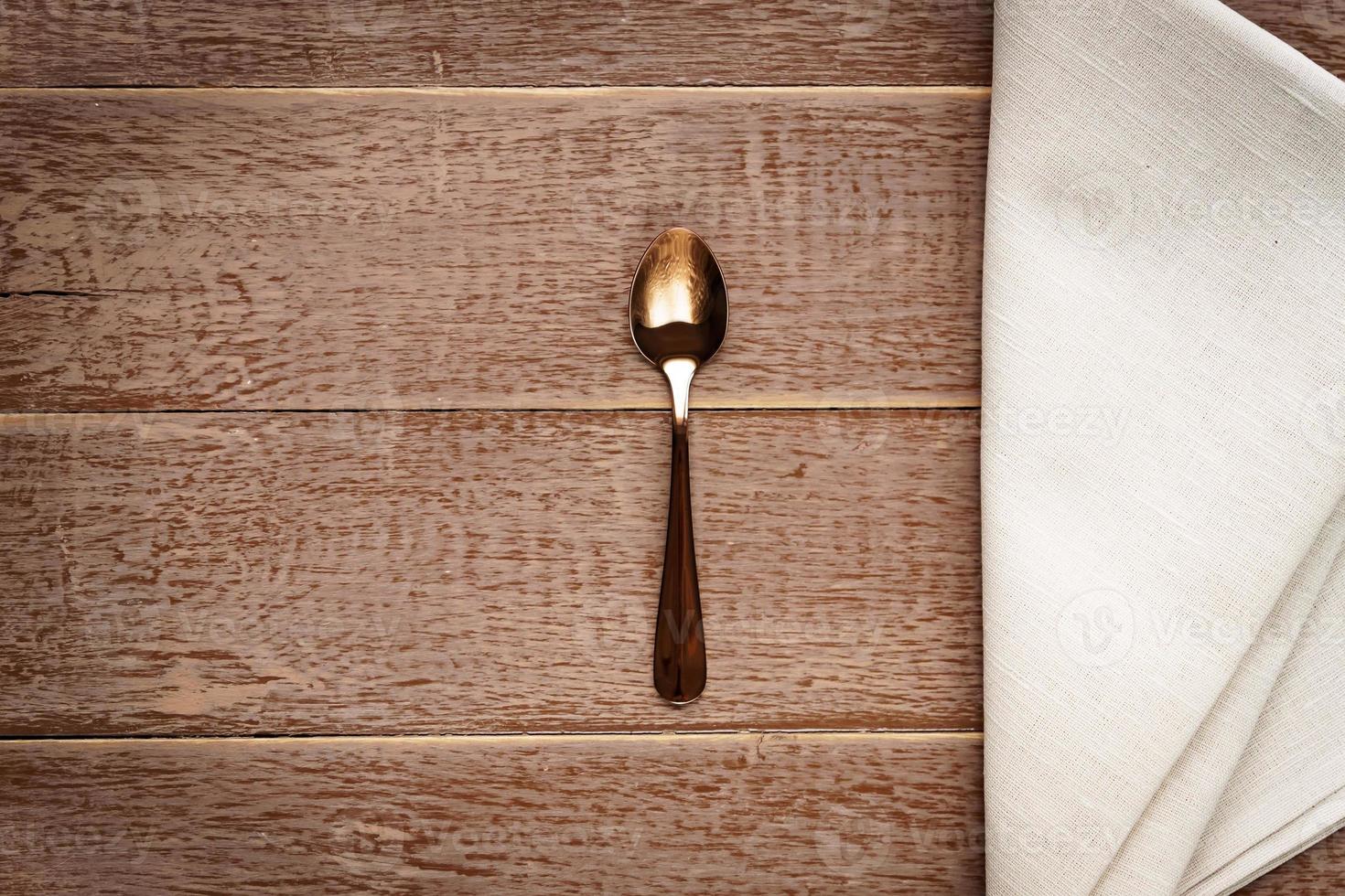 Top view of cloth napkin of beige color and served tea spoon on wooden table. photo