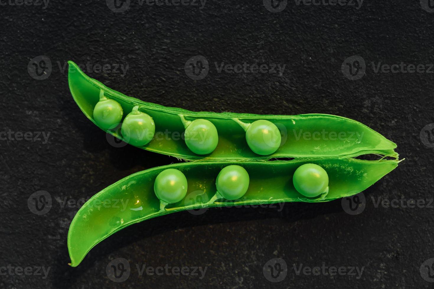 Vegetable backdrop vith copy space for your projects. Close up of fresh ripe green peas on black background photo