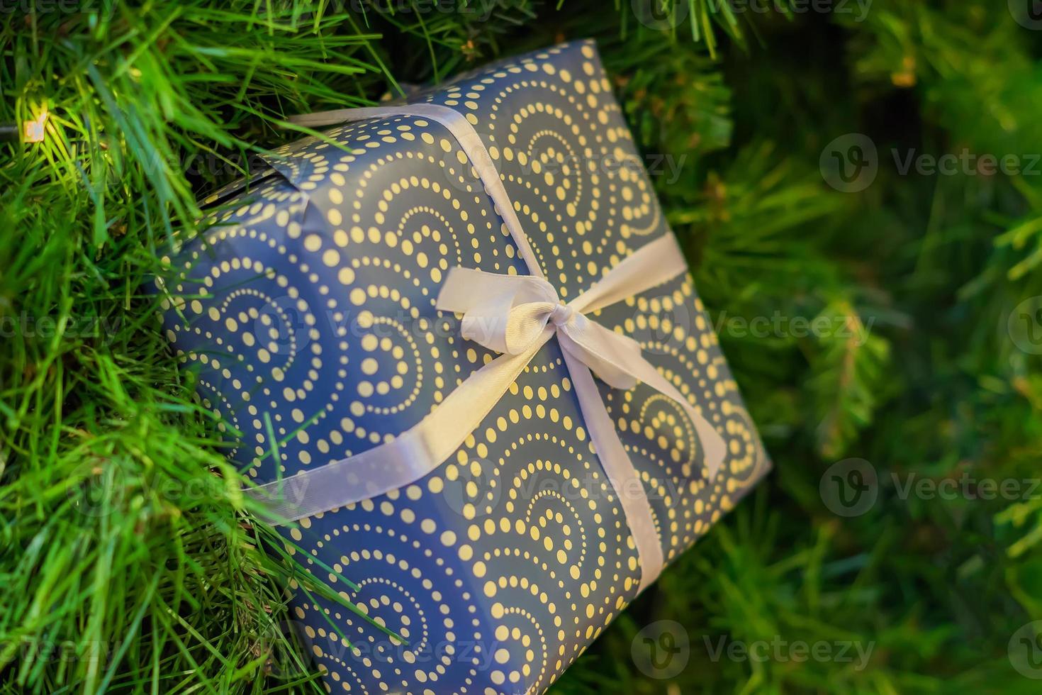 Christmas and New Year holidays background. Christmas tree with garland and giftbox with a bow photo