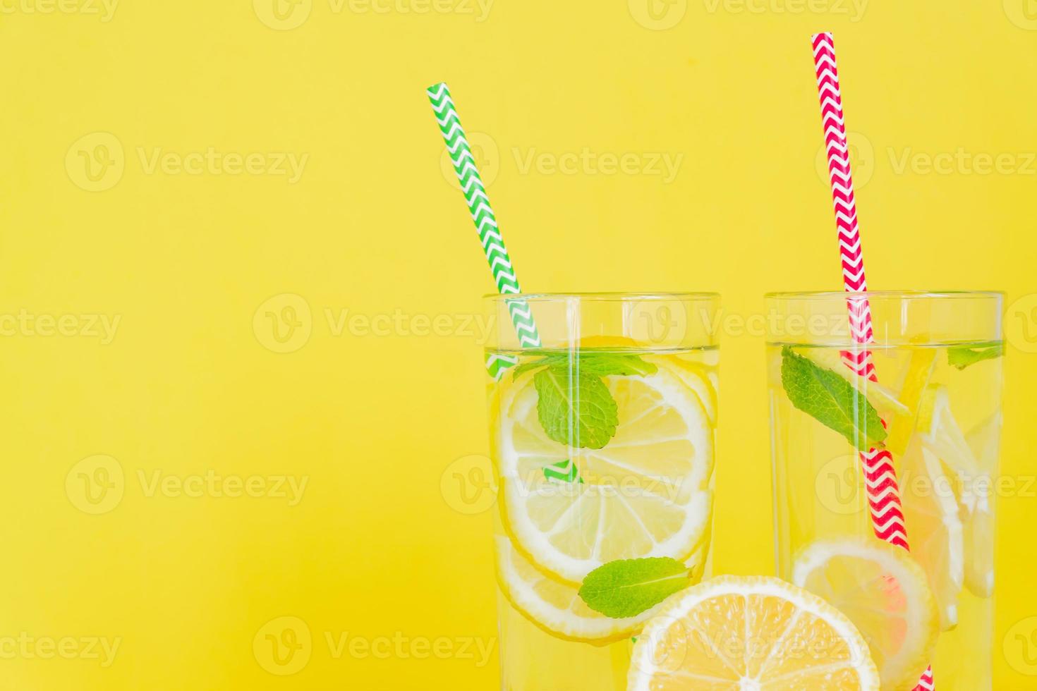 Homemade lemonade with lemon and mint on colored yellow background. Summer cold drink cocktail. Copyspace photo