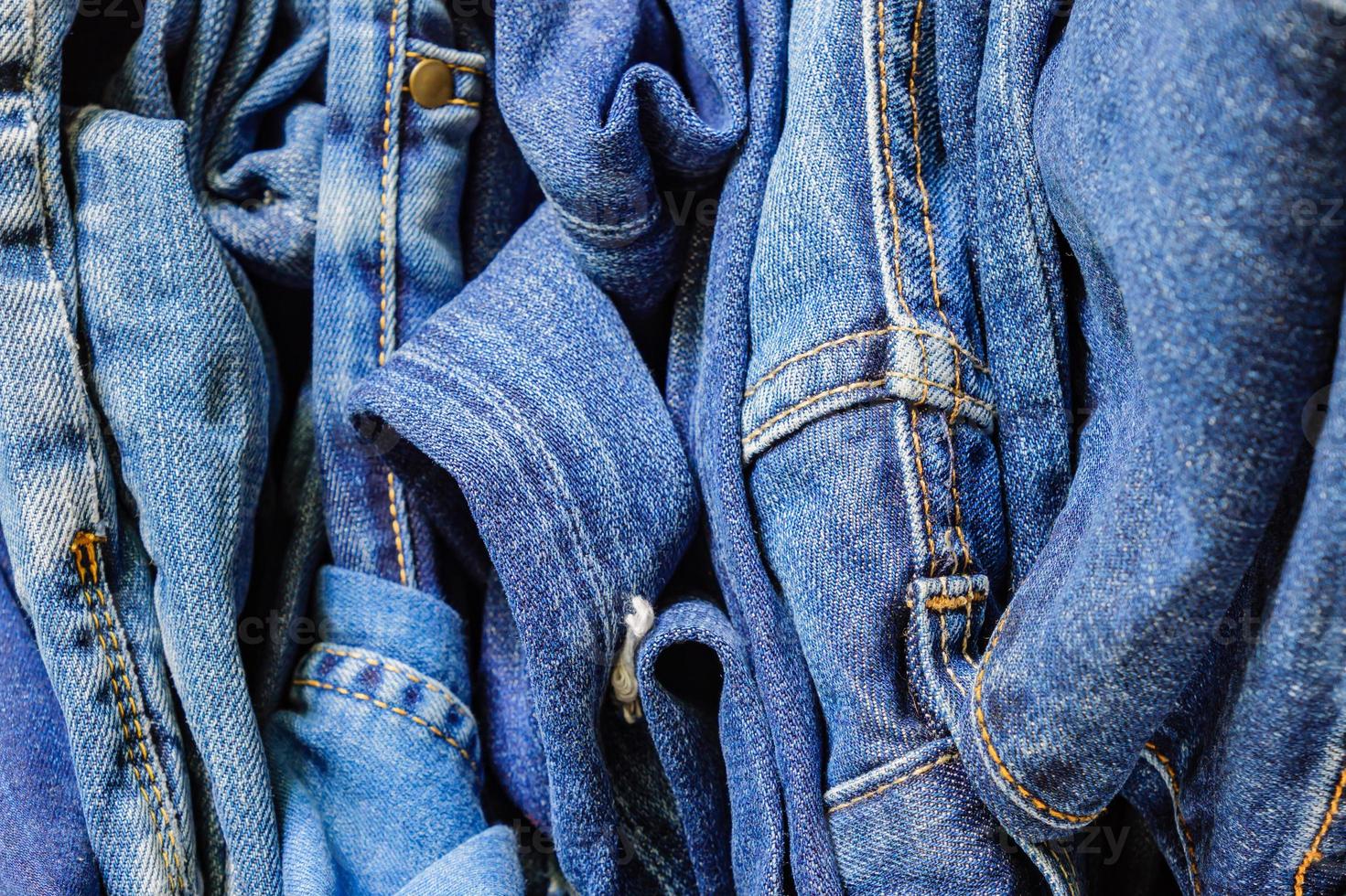 Pile of blue denim jeans. Background texture. Beauty and fashion concept. photo