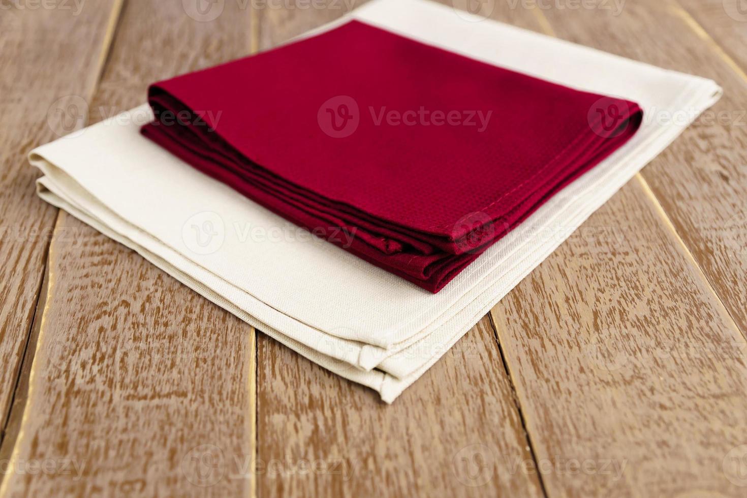 close up of cloth napkins of beige, and burgundy colors on rustic brown wooden table. Shallow depth of field. photo