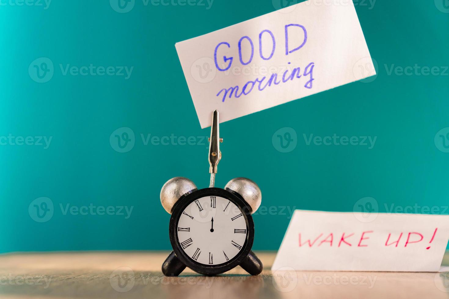 Alarm clock and banner with handwritten phrase good morning on wooden table. Time management concept. photo