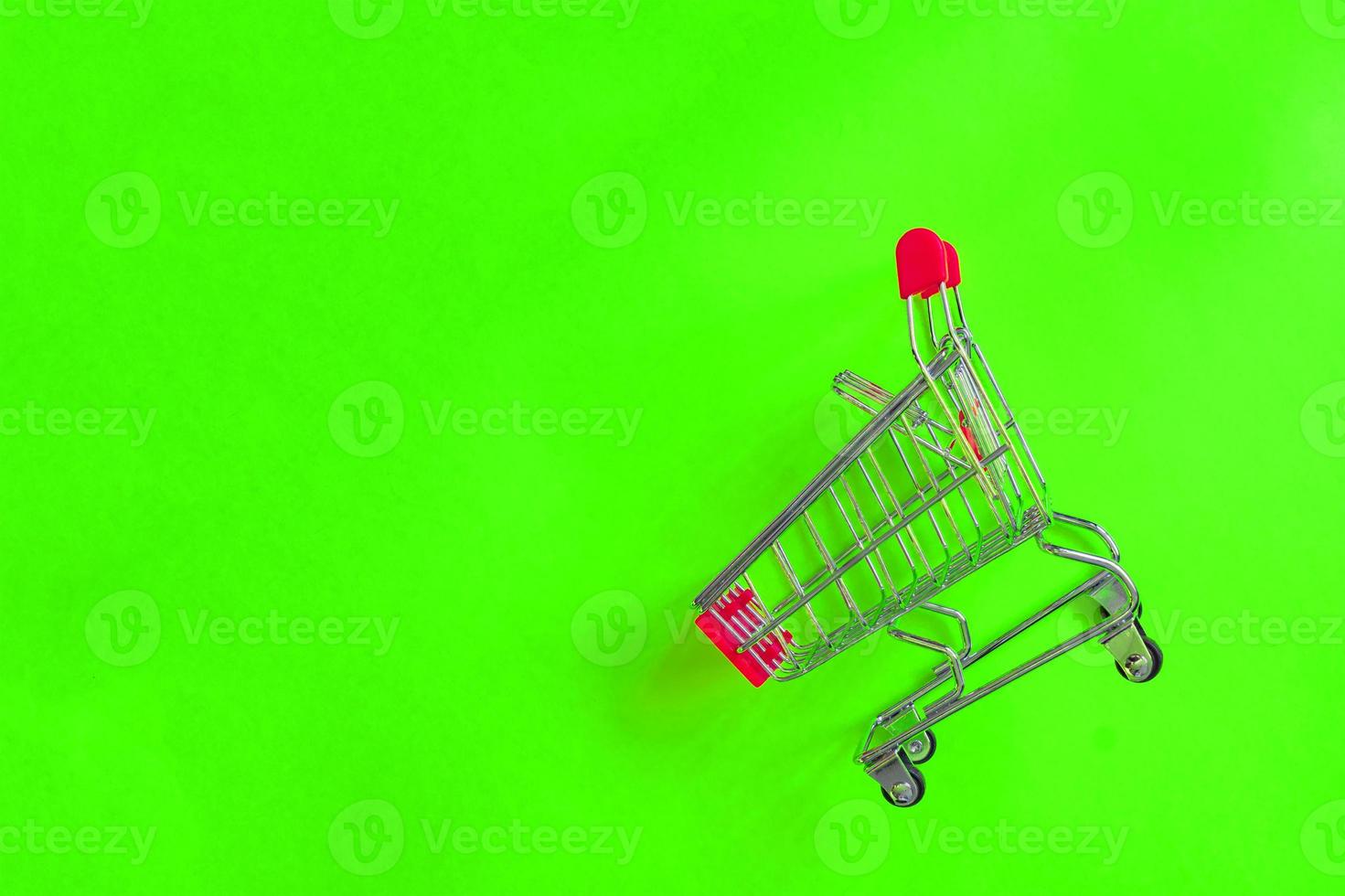 Empty shopping cart on green background. Top view, minimal flat lay. photo