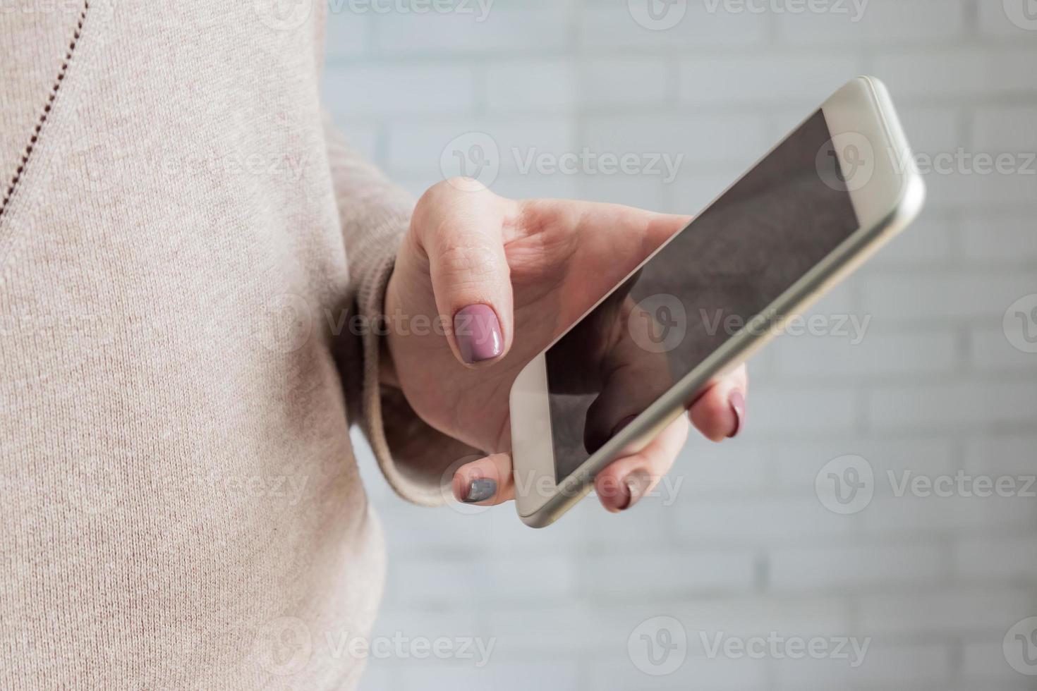 Woman holding white smatphone in her hand with trendy manicure. Selective focus photo