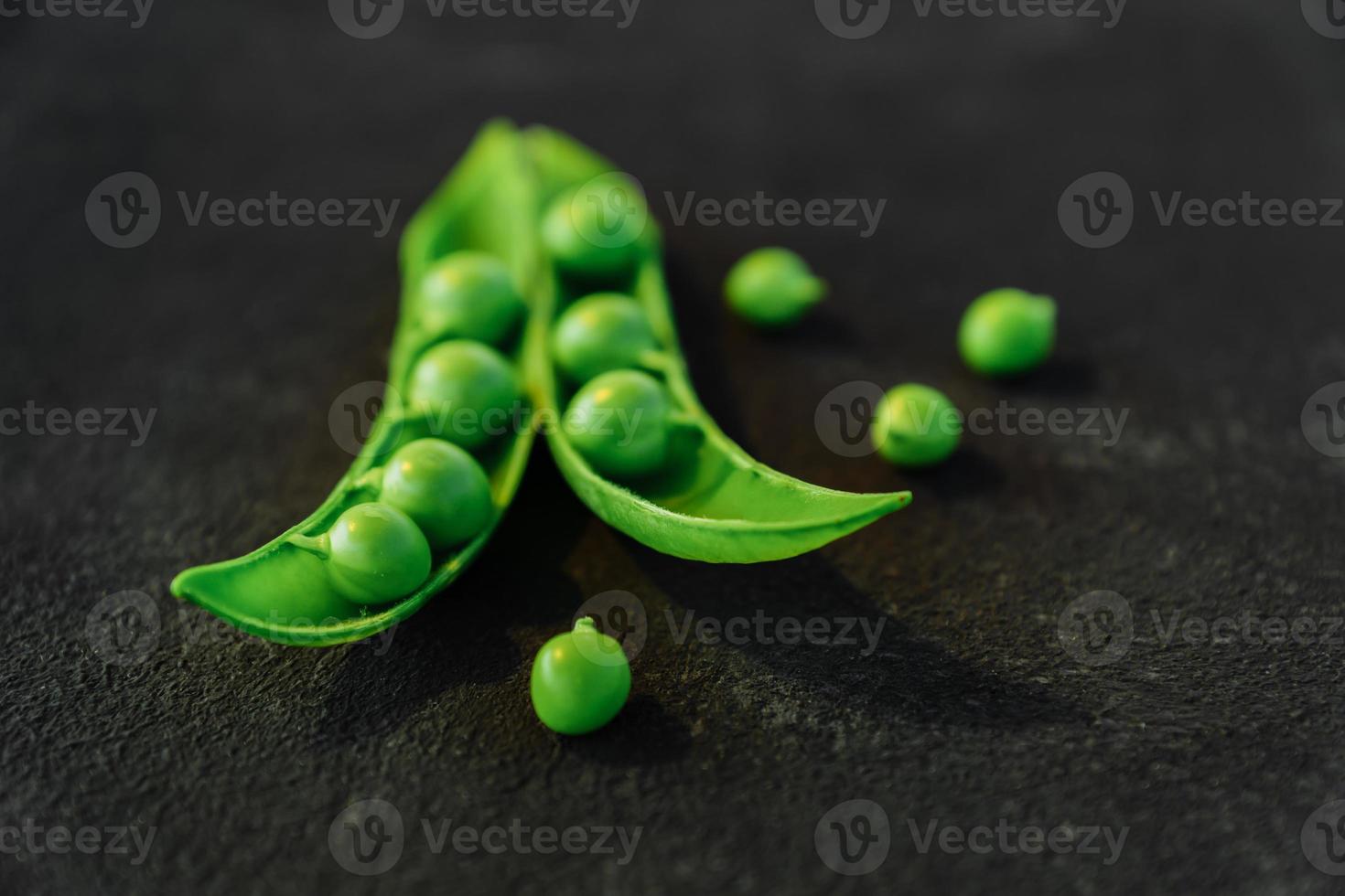 Close up of fresh ripe green peas on black background. Healthy organic food photo