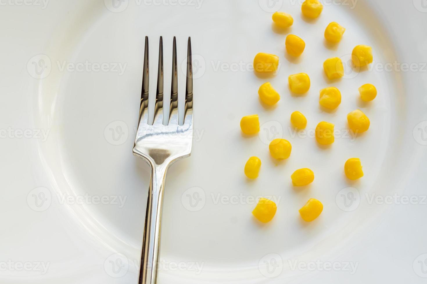 Top view of sweet corn on white plate and steel fork photo