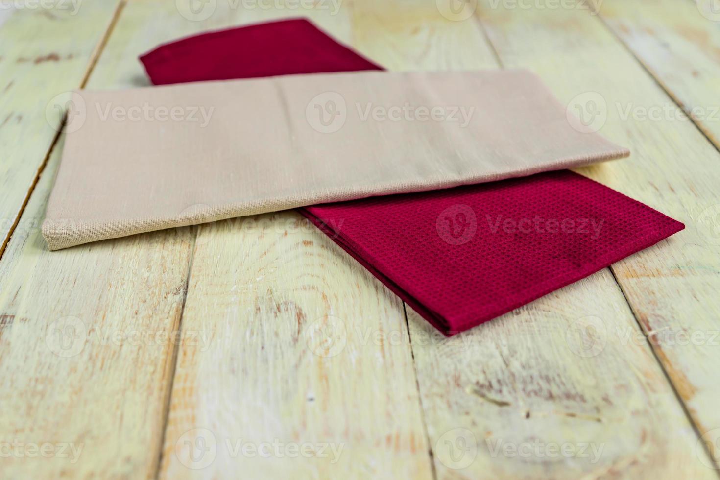 perspective view of cloth napkins of beige and burgundy colors on rustic white wooden table. Shallow depth of field. photo