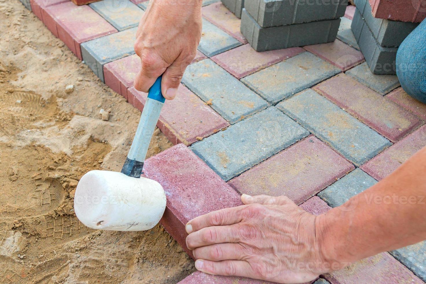 Worker laying red and gray concrete paving blocks. Road Paving, construction. photo