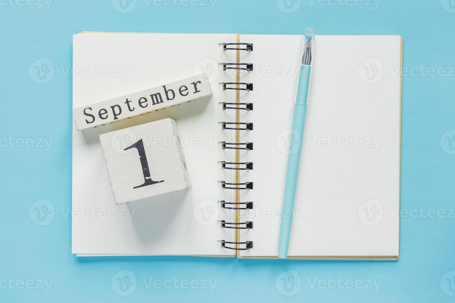 1 de septiembre en un calendario de madera en un libro de texto de estudio sobre fondo azul. concepto de regreso a la escuela foto