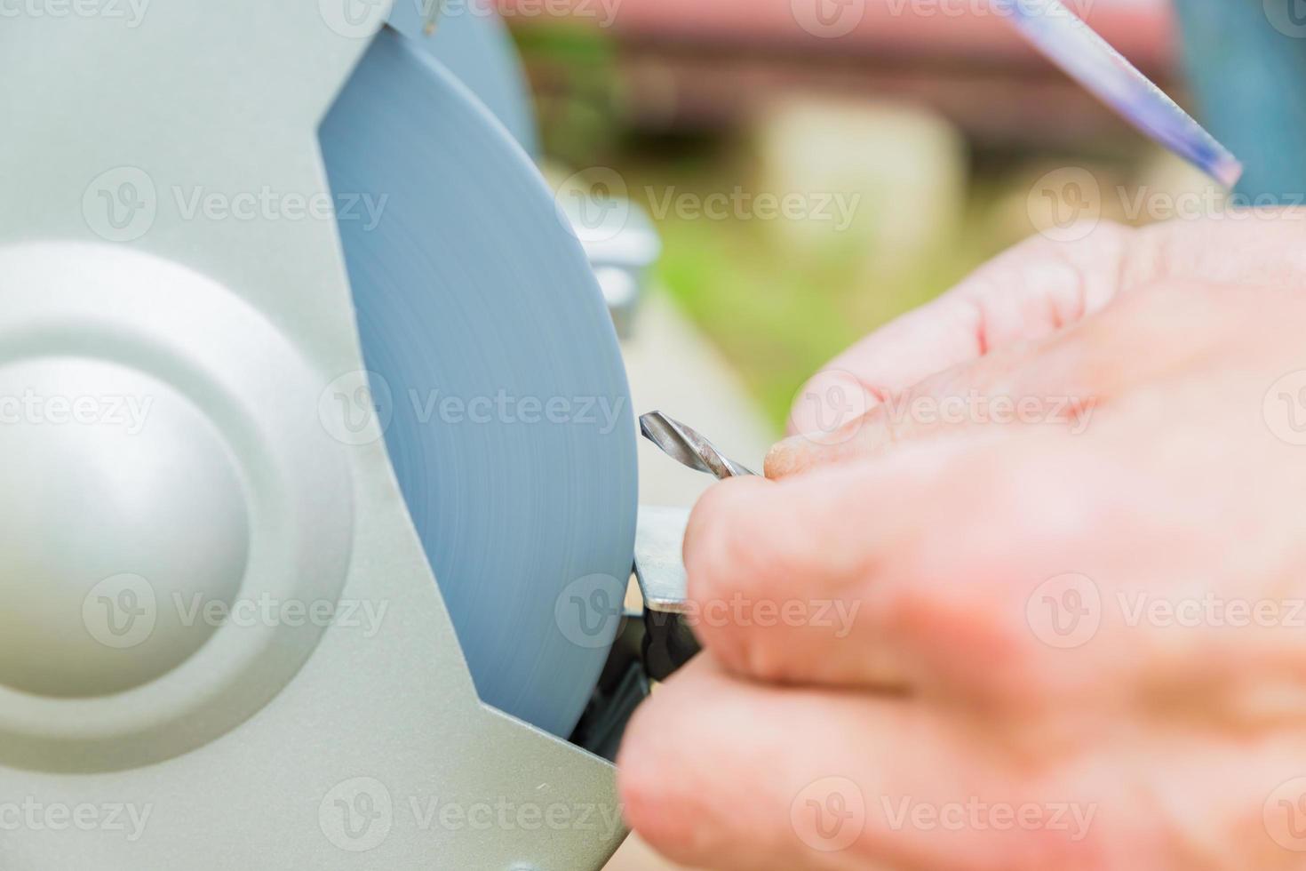 Close up of Industrial worker sharpening drill with grindstone abrasive disc cutter machine photo