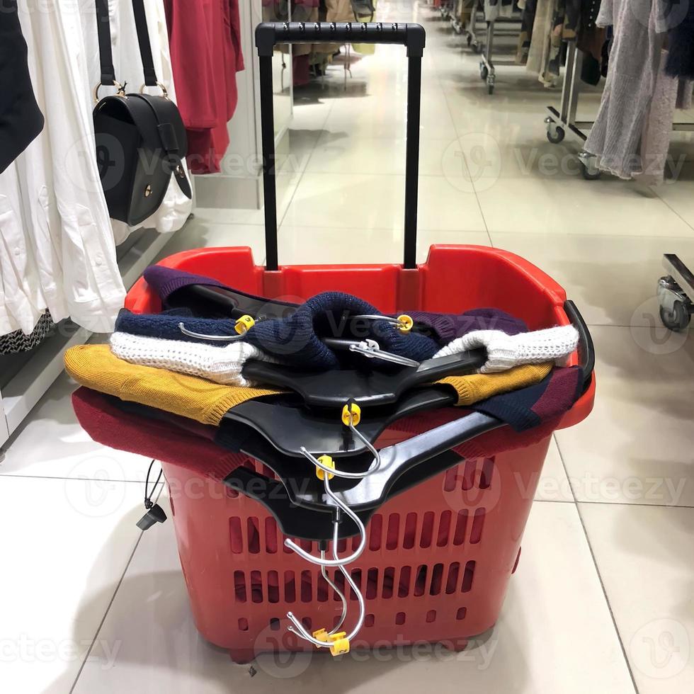 Red plastic shopping cart fool of women'd clothing at store photo