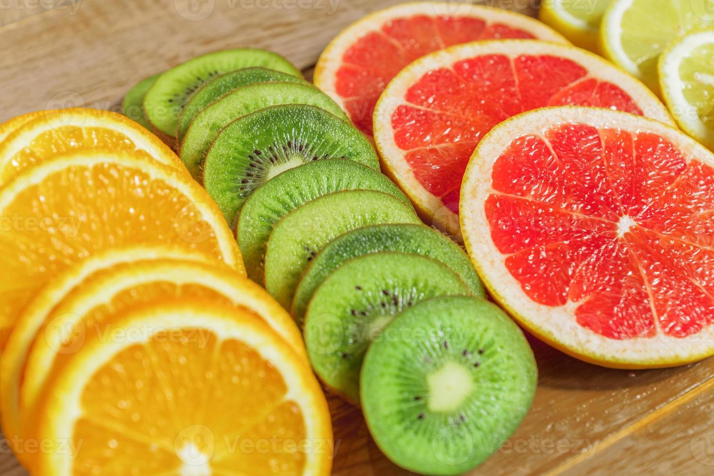 frame with slice of oranges, lemons, kiwi, grapefruit pattern on wooden background. copy space. photo