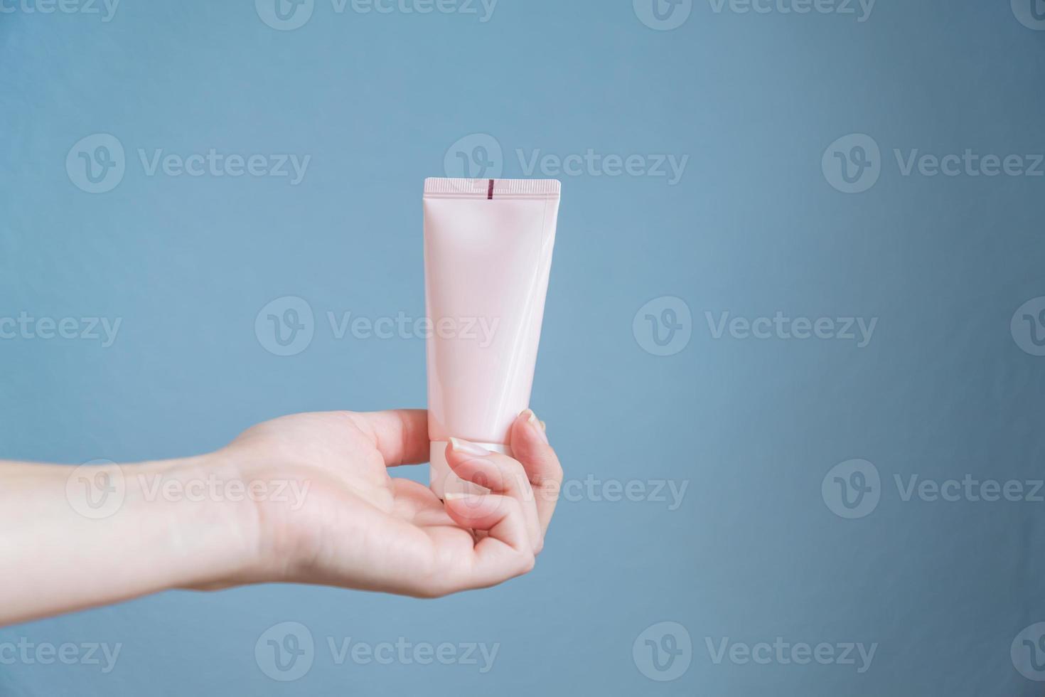 woman holding moisturizing cream. Pink tube in female's hands photo