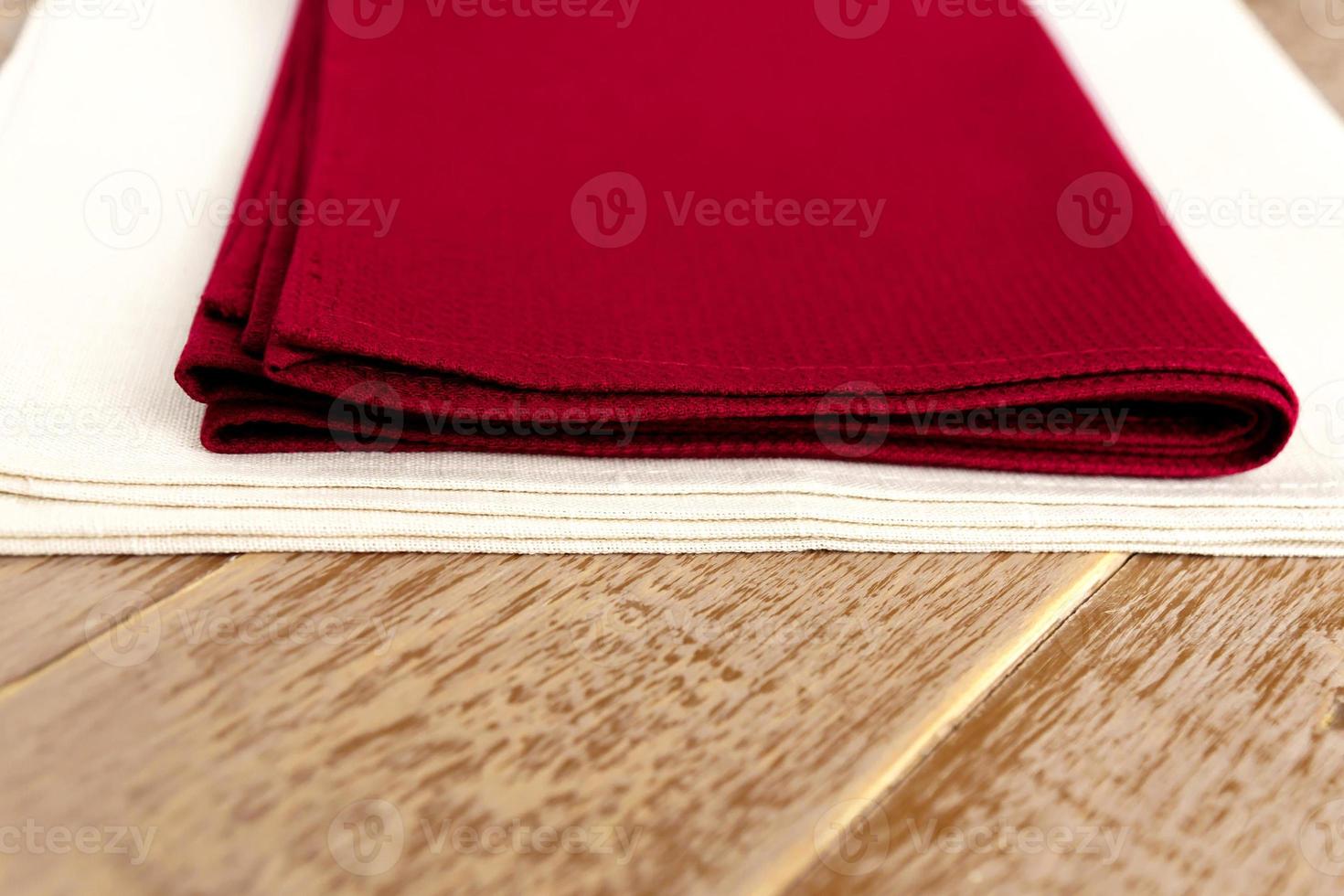 close up of cloth napkins of beige, and burgundy colors on rustic brown wooden table. Shallow depth of field. photo