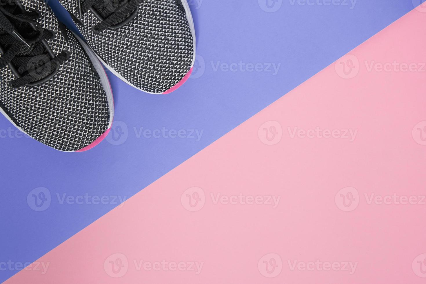 Black and white sneakers with pink sole on ultra violet and pink background. Concept of healthy lifestile and everyday training. Top view with copy space for your project photo