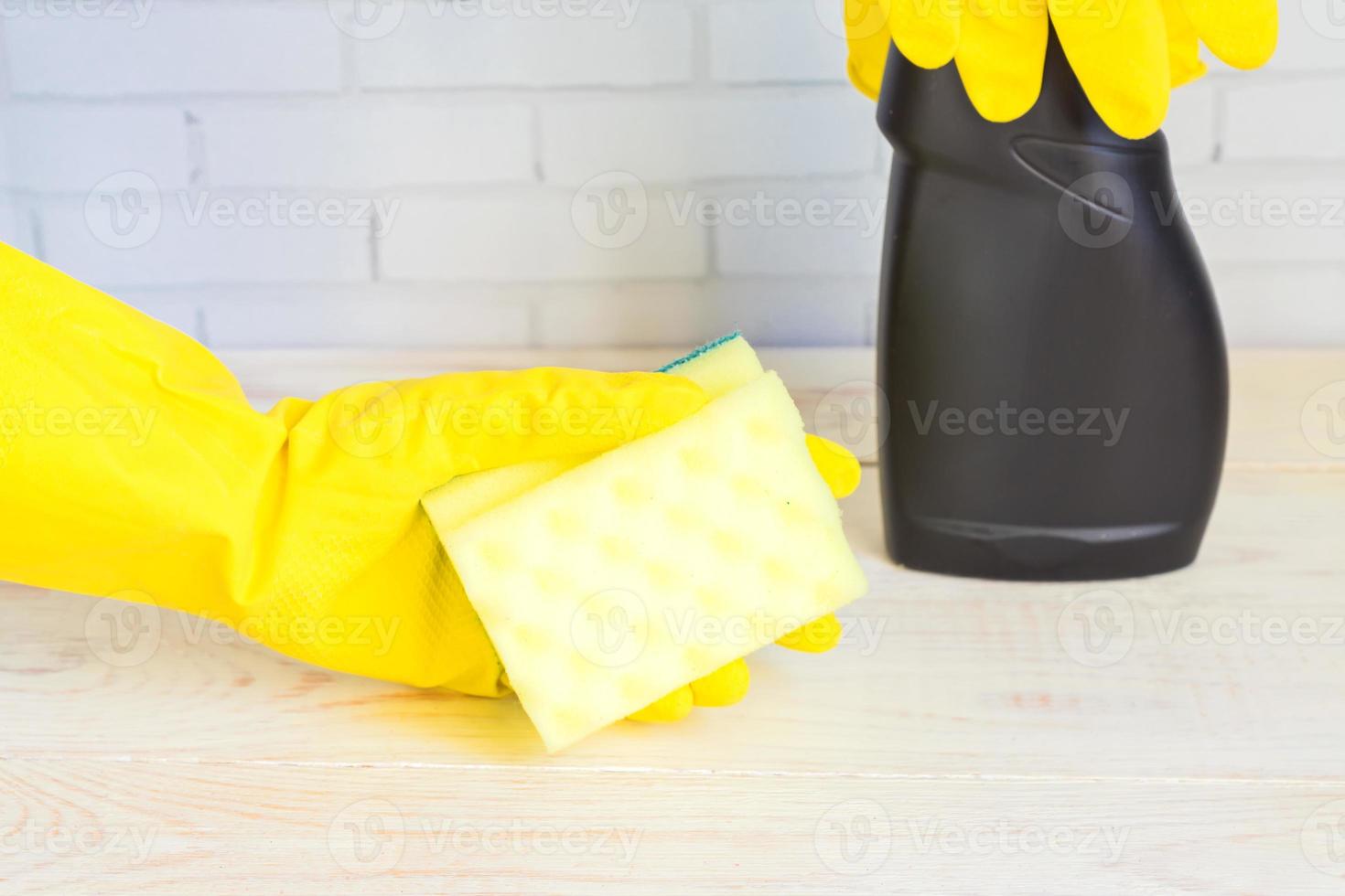 mano de mujer en guante de goma amarillo con esponja de limpieza. Producto de limpieza. foto