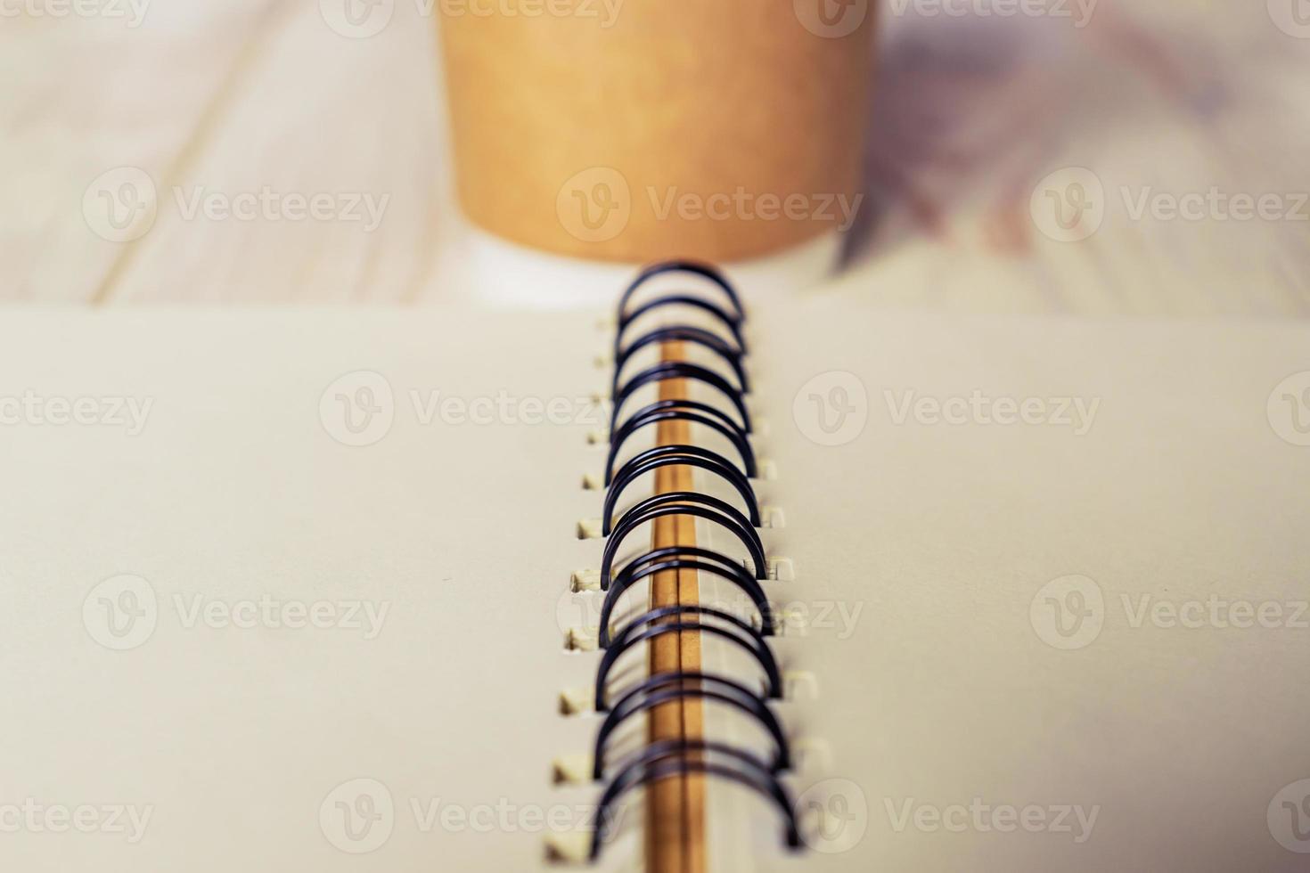 craft paper coffee cup and open notebook diary with copy space on wooden table photo