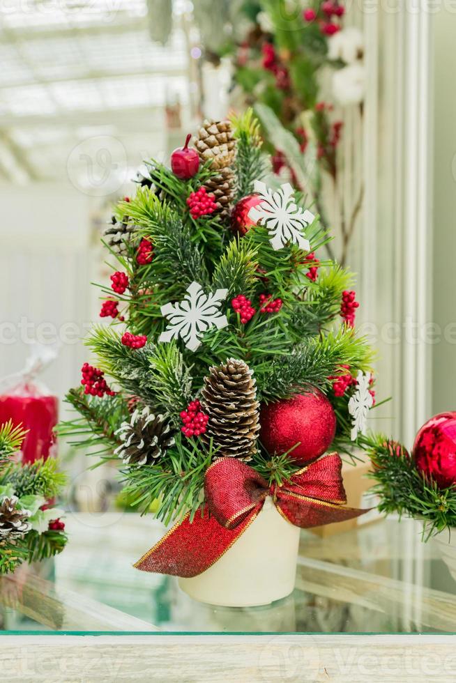composición interior de chritms festivos. ramas de abeto y bayas rojas decoradas con conos, adornos y lazos en maceta blanca. foto