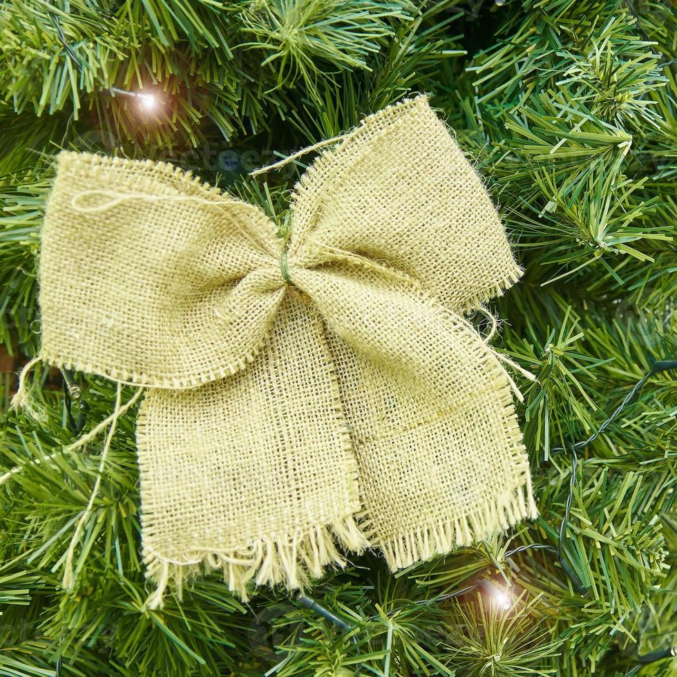 Canvas bow and led garland on fir tree. Christmas and new year background for greeteng card. photo