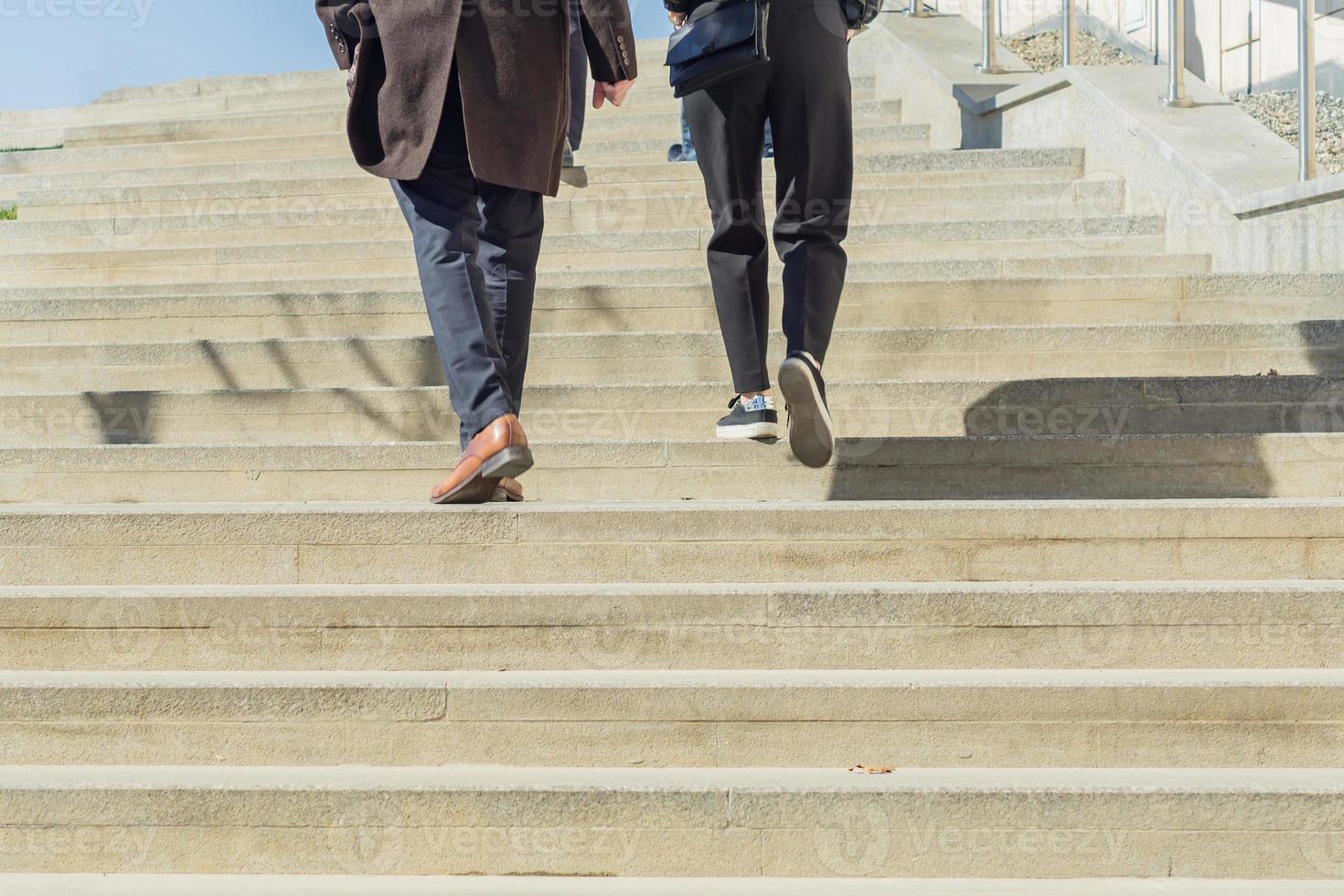 Two people in business casual wear walking upstairs outdoors. Urban background photo