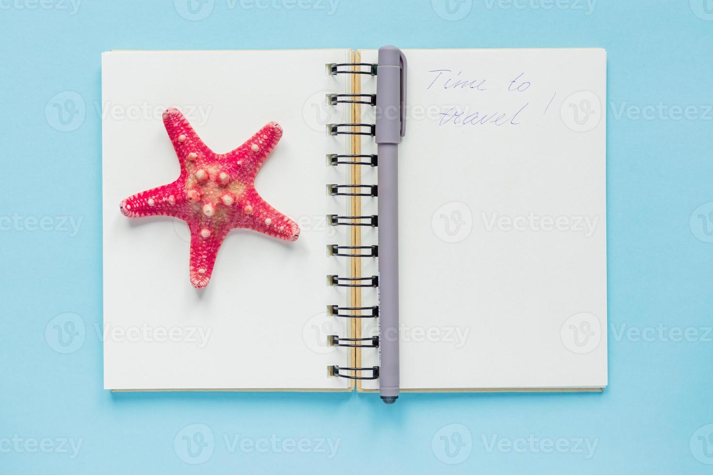 Top view of open empty notebook with starfish and time to travel inscription on pastel blue colorful background. Travel and holiday concept photo