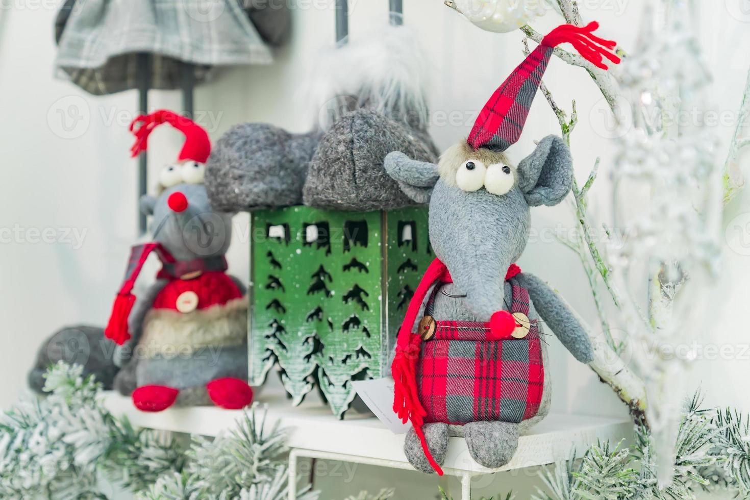 Symbol of the year 2020. White toy rat in christmas hat hanging on fur snowy tree. Festive Interior decoration. photo