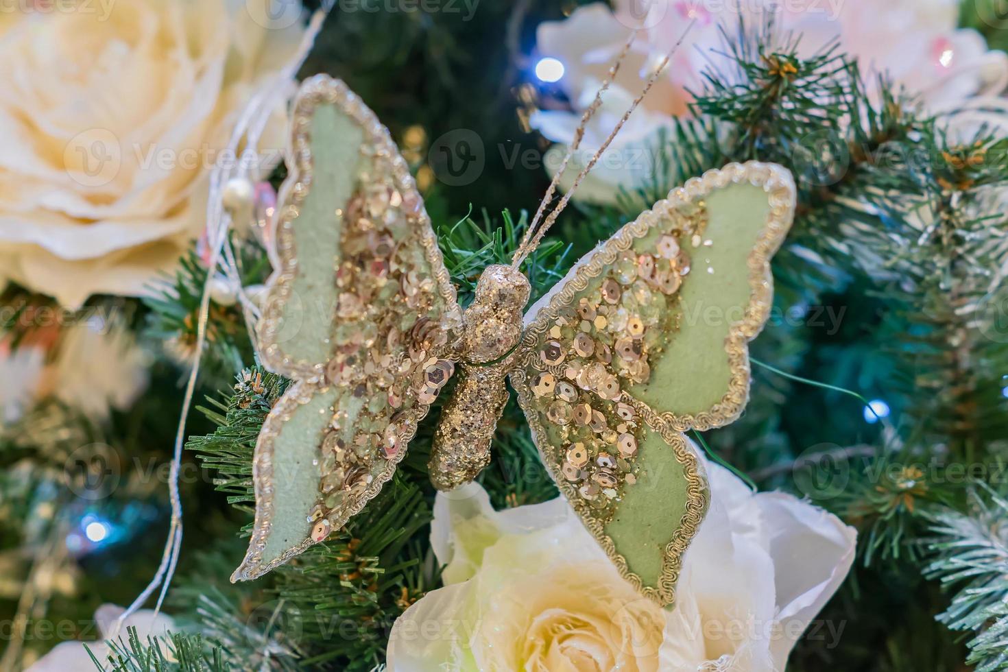 close up of christmas tree decorated with butterfly and tender pink flower. photo