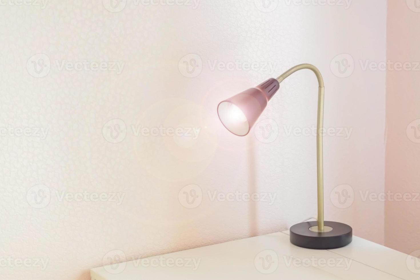 Desk lamp with light on of white table, freelance working place concept photo