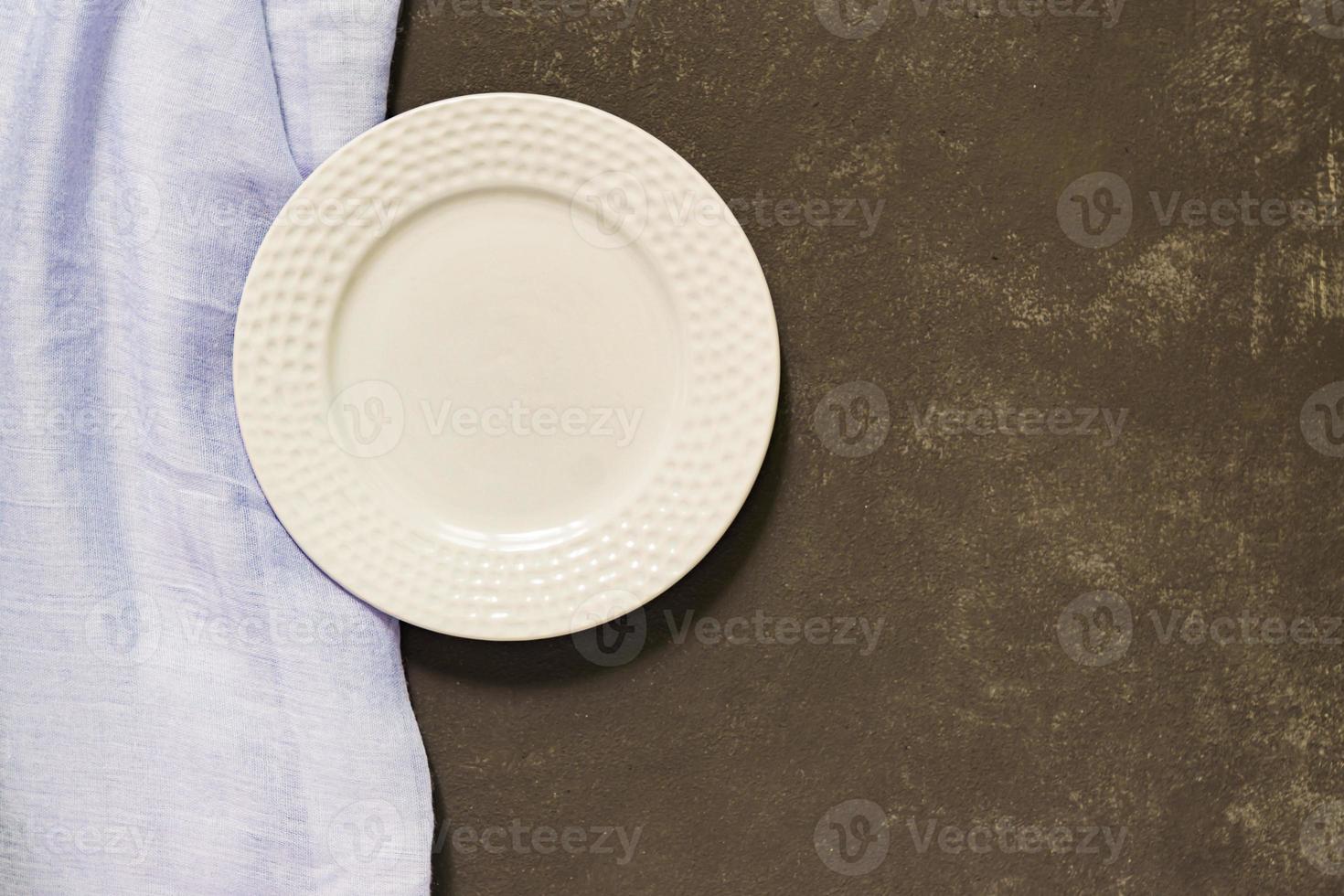 Top view of empty served plate, blue textile on black concrete background. Copy space. photo
