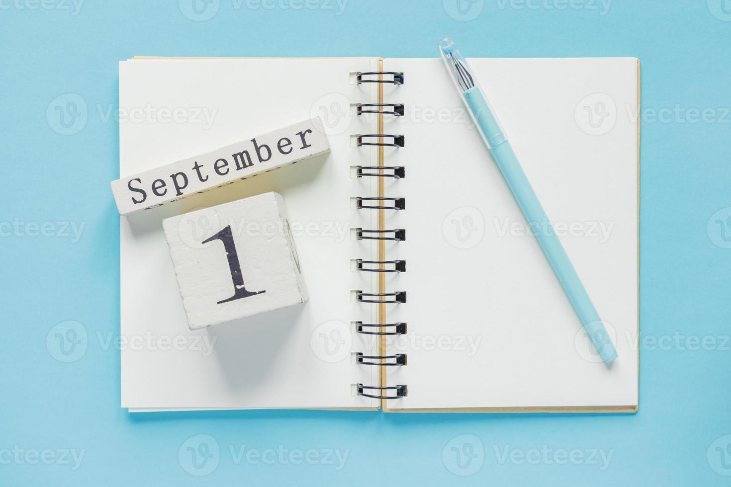 1 de septiembre en un calendario de madera en un libro de texto de estudio sobre fondo azul. concepto de regreso a la escuela foto