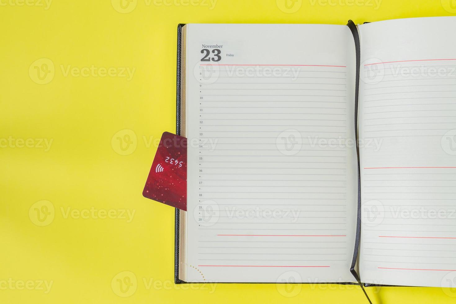 Black friday sale concept. Shopping list in notebook and bank card as bookmark on yellow backgrond photo