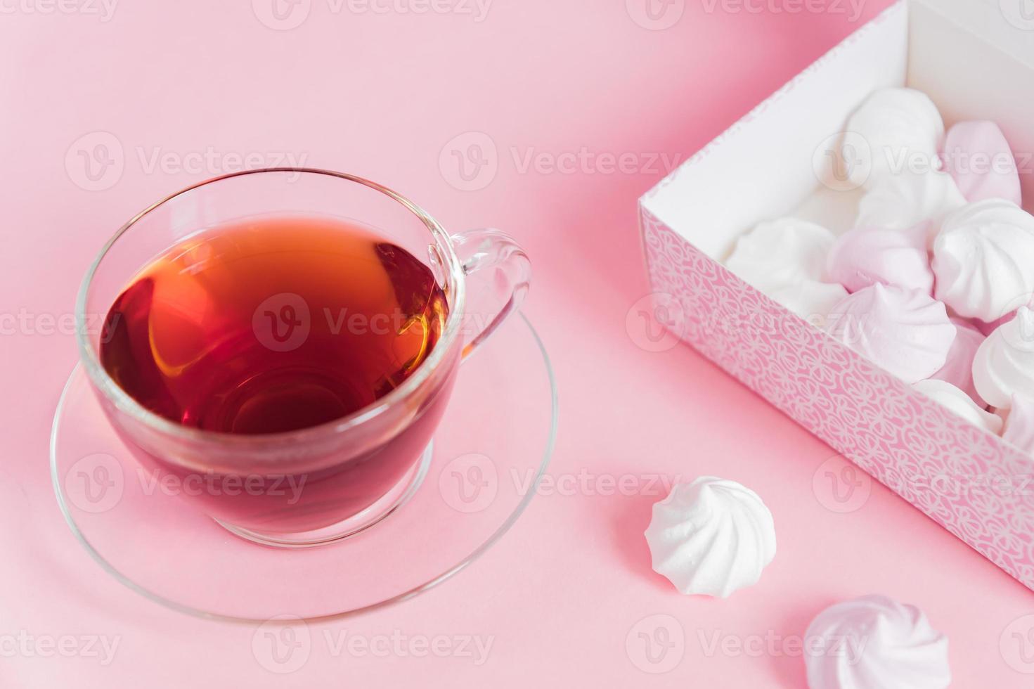 White and pink twisted meringues and cup of tea on pink background. French dessert prepared from whipped with sugar and baked egg whites. Greeting card with copy space photo
