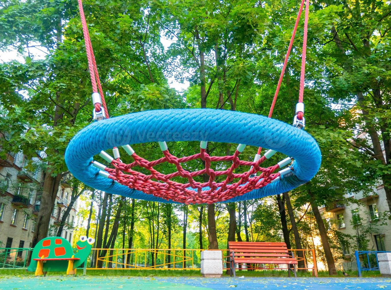 Round swing seat made of mesh in playground. Empty blue rope web nest for swinging closeup. photo